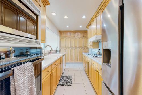 a kitchen with wooden cabinets and a stainless steel refrigerator at Tierra De La Maracuyá in Fallbrook