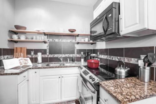 a kitchen with white cabinets and a stove top oven at Chic 1BR Retreat with Sofa Bed, Free Parking in Indianapolis