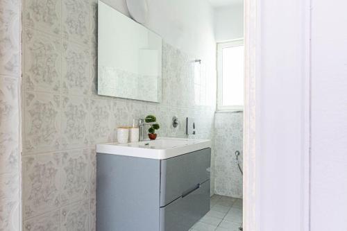 a white bathroom with a sink and a mirror at Himara City 24 - Central & Beach Access in Himare