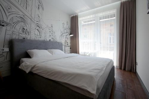 a bedroom with a white bed with a large window at Old City apart in Lviv