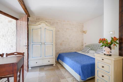 a bedroom with a blue bed and a desk at Trullimania in Alberobello