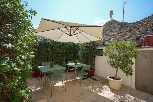 a patio with two tables and an umbrella at Trullimania in Alberobello