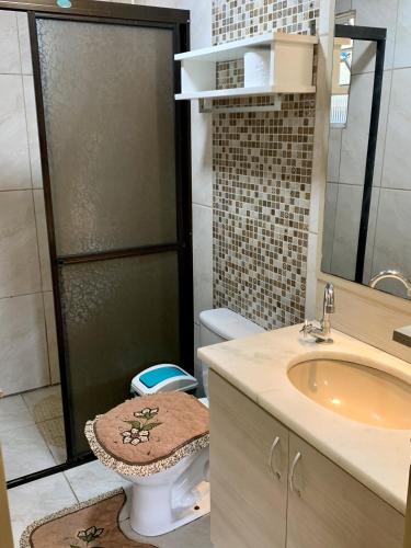 a bathroom with a shower with a toilet and a sink at Fique a poucos passos do Centro e da Praia - Jô in Torres