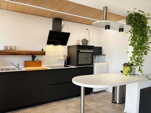 a kitchen with black cabinets and a white table at Der Eulenschlupf in Ühlingen-Birkendorf