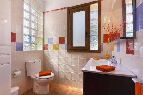 a bathroom with a toilet and a sink and a mirror at Villa Angel by Villa Plus in Son Xoriguer