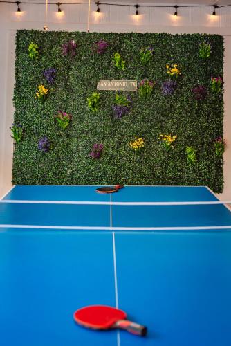 a tennis court with a green wall with flowers at Beautiful Texas Ranch House, Game Room & Minigolf in San Antonio