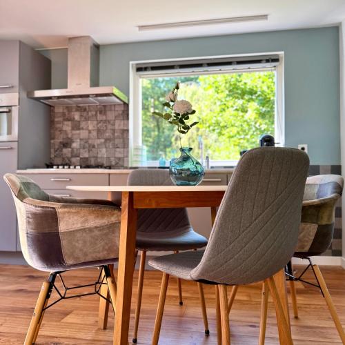 a dining room table with chairs and a window at B&B Eekhoornpad in Tilburg