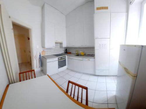 a kitchen with white appliances and a table and chairs at Ampie camere Locarno in Locarno