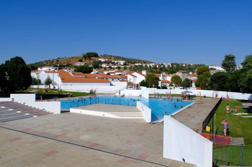a large swimming pool with people standing around it at Matriz Guest House in Portel