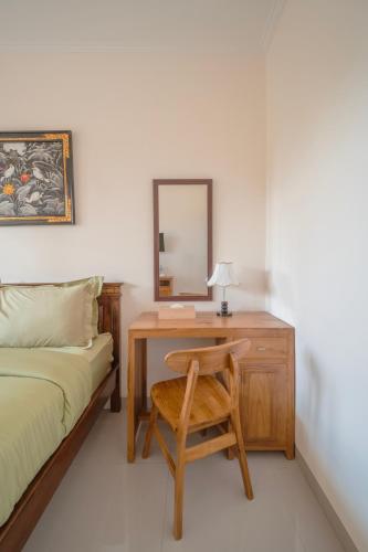 a bedroom with a desk with a bed and a mirror at Titeng Guest House - Comfortable studio in amazing location near Potato Head and the beach in Seminyak