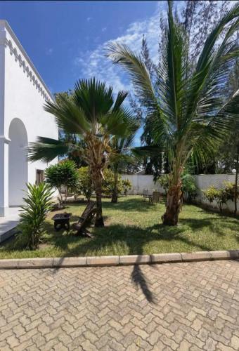 a group of palm trees in a yard next to a building at Clem Villa in Ukunda
