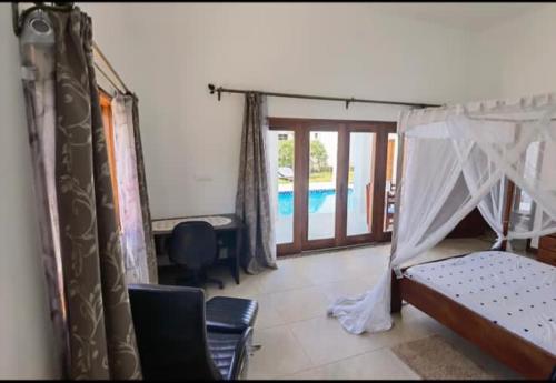 a bedroom with a bed and a swimming pool at Clem Villa in Ukunda