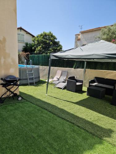 un groupe de chaises sous une tente sur une pelouse dans l'établissement Villa avec piscine climatisation et parking, à Saint-Jean-de-Védas