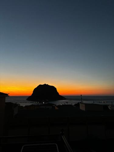 a sunset over a beach with a rock in the ocean at Kanelli΄s apartments in Monemvasia
