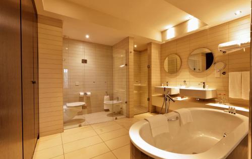 a bathroom with a tub and a toilet and a sink at Labadi Beach Hotel in Accra