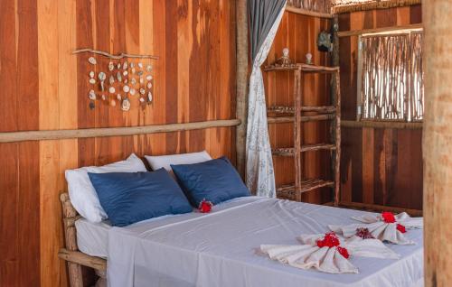 a bed with white sheets and red flowers on it at Vila Barrinha in Acaraú
