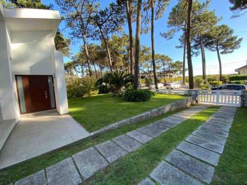 een huis met een oprit en een grasveld bij Coral Beach House in Viana do Castelo