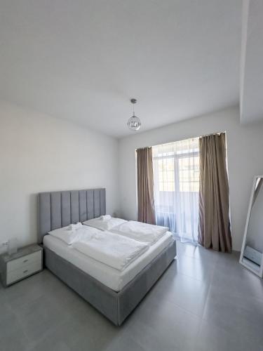 a white bedroom with a bed and a large window at Silver Moon Residence 3 in Arad