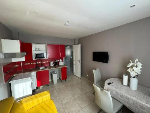 - une cuisine avec des placards rouges et une table dans une pièce dans l'établissement Appartement moderne à Villiers-le-Bel - 35 m² - Pour 4 personnes., à Villiers-le-Bel