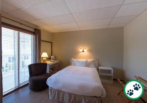 a hotel room with a bed and a chair at Hôtel Aquamer in Carleton sur Mer