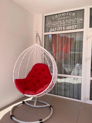 a red chair sitting in a room with a window at Apartment near the sea in Gribovka