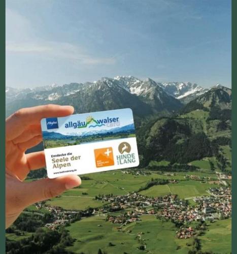 a person holding up a credit card with mountains in the background at Bergnest Iseler mit Panoramablick in Oberjoch