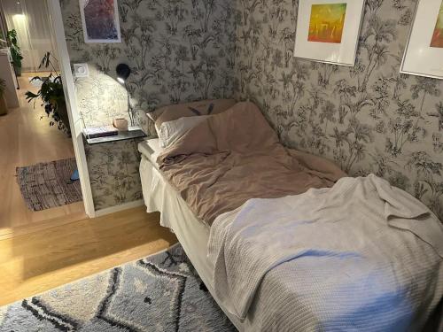 a unmade bed in a bedroom with wallpaper at Villa i lugnt område nära hav in Ystad