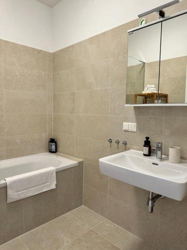 a bathroom with a tub and a sink and a mirror at City Apartment nahe Schönbrunn 13 in Vienna