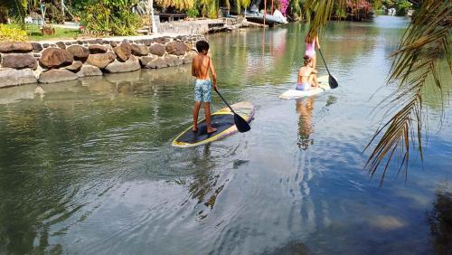 two children are on paddle boards in the water at MOOREA - Bungalow Moekea Lagoon in Hauru
