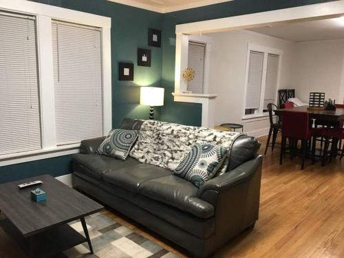 a living room with a leather couch and a table at Center Midtown WalkUp in Omaha