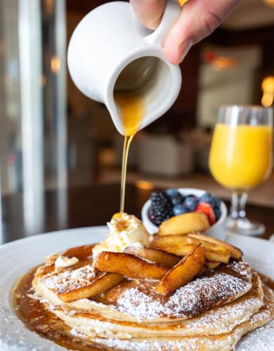 a person pouring syrup onto a stack of french toast at The Westin Crystal City Reagan National Airport in Arlington