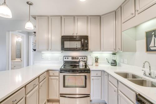 a kitchen with white cabinets and a stove top oven at Darien Condo with Boat Dock Access Walk to Downtown in Darien