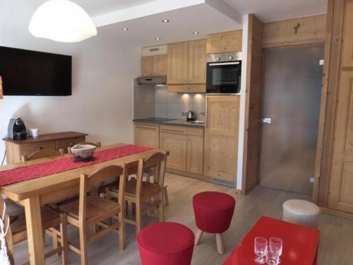 une cuisine avec une table en bois et des chaises rouges dans l'établissement Résidence Trois Marches Bat C - Joli appartement rénové avec une belle vue, proche du télésiège du morel et de l'arrêt de bus MAE-1778, à Les Allues