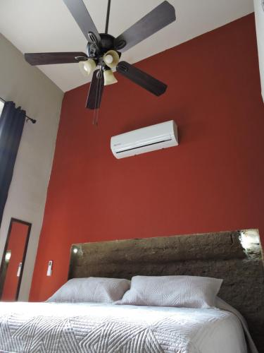 a ceiling fan in a bedroom with a red wall at Alojamiento Suite con Aire Acondicionado y Estacionamiento ubicado a 1 cuadra del Parian en Centro Tlaquepaque Privada e Independiente in Guadalajara