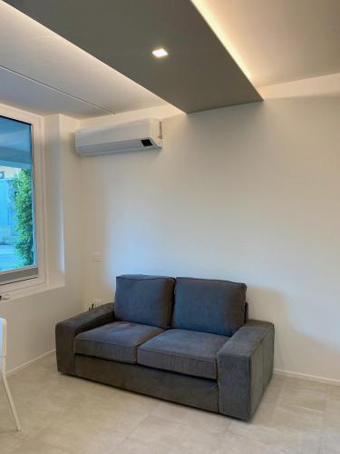 a couch sitting in a living room with a window at NEW Residenza le Essenze - i 7 Laghi in Erba