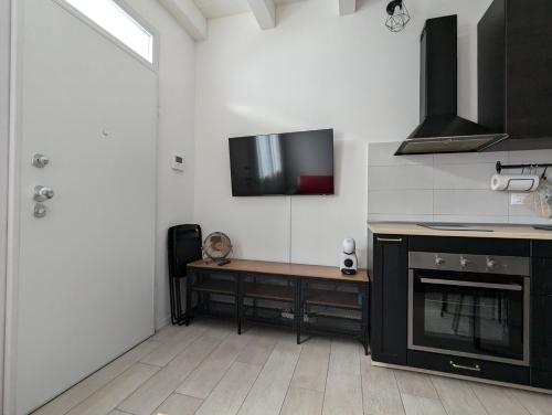 a kitchen with a stove and a tv on the wall at Berretta Rossa in Bologna