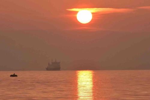 a boat in the water with the sun in the sky at Fraoch, Pets welcome in Port Bannatyne
