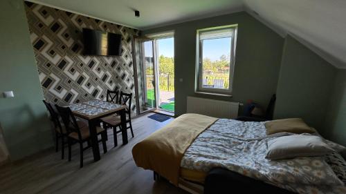 ein Schlafzimmer mit einem Bett und einem Tisch und einem Fenster in der Unterkunft Domek NA SKRAJU WSI, APARTAMENTY in Górki Wielkie