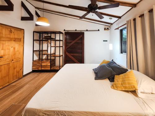 a bedroom with a large bed with a ceiling fan at Calala Lodge in Cabuya