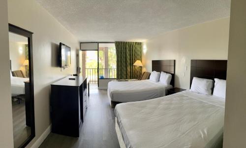 Una habitación de hotel con dos camas y balcón. en Rodeway Inn Davenport-Champions Gate, en Davenport