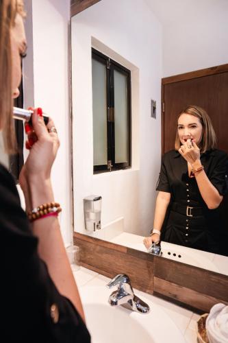 a woman brushing her teeth in front of a bathroom mirror at Hotel del Carmen, en el Centro- DESAYUNO Incluido ! in Tuxtla Gutiérrez