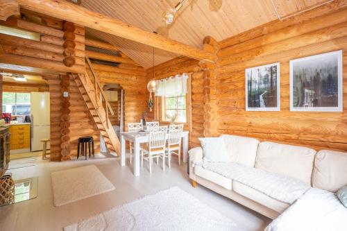 ein Wohnzimmer mit einem weißen Sofa in einer Blockhütte in der Unterkunft Lapin Villa Hiisi joen rannalla in Ranua