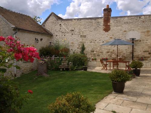 a garden with a table and an umbrella at Relais De La Haute Pommeraye in Apremont