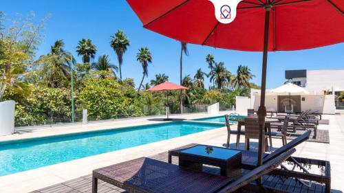 a swimming pool with a red umbrella and chairs and a table with a table at Nayarit Coastal Retreat New Luxury Haven in Nuevo Vallarta