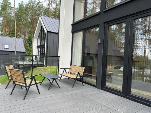 a patio with two chairs and a table on a house at Dolina Ciszy - Wypoczynek i relaks pod sosnami in Łubiana