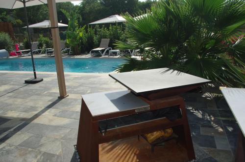 a table and bench next to a swimming pool at chambre villa 4 in Servas