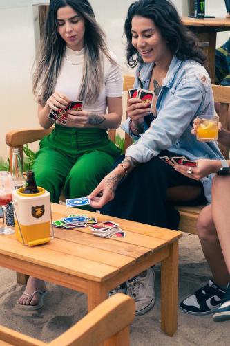 three women sitting around a table looking at their cell phones at Graffi Beach House in Florianópolis