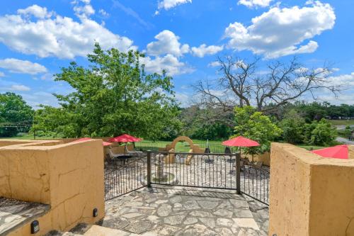 a patio with red umbrellas and tables and chairs at Blanco Riverside Cottages in Blanco