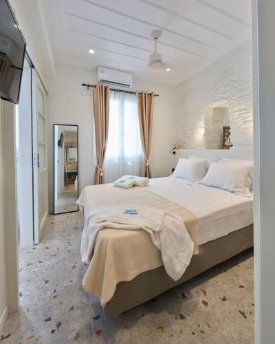 a white bedroom with a large bed and a mirror at Apaggio Boutique House in Andros