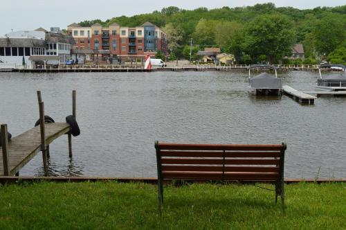 a bench sitting in the grass next to a body of water at Casual Living Extended Stay Hotels in Algonquin